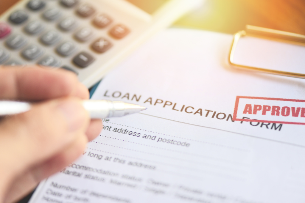 Close-up of a construction loan application form stamped approved with calculator and pen on desk